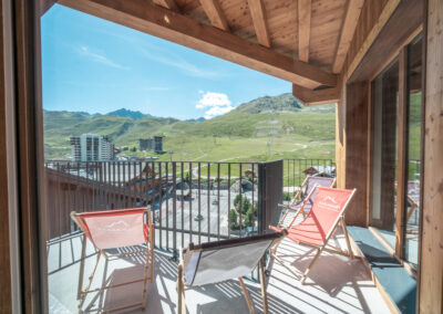 Un balcon avec chaises et vue sur les montagnes.